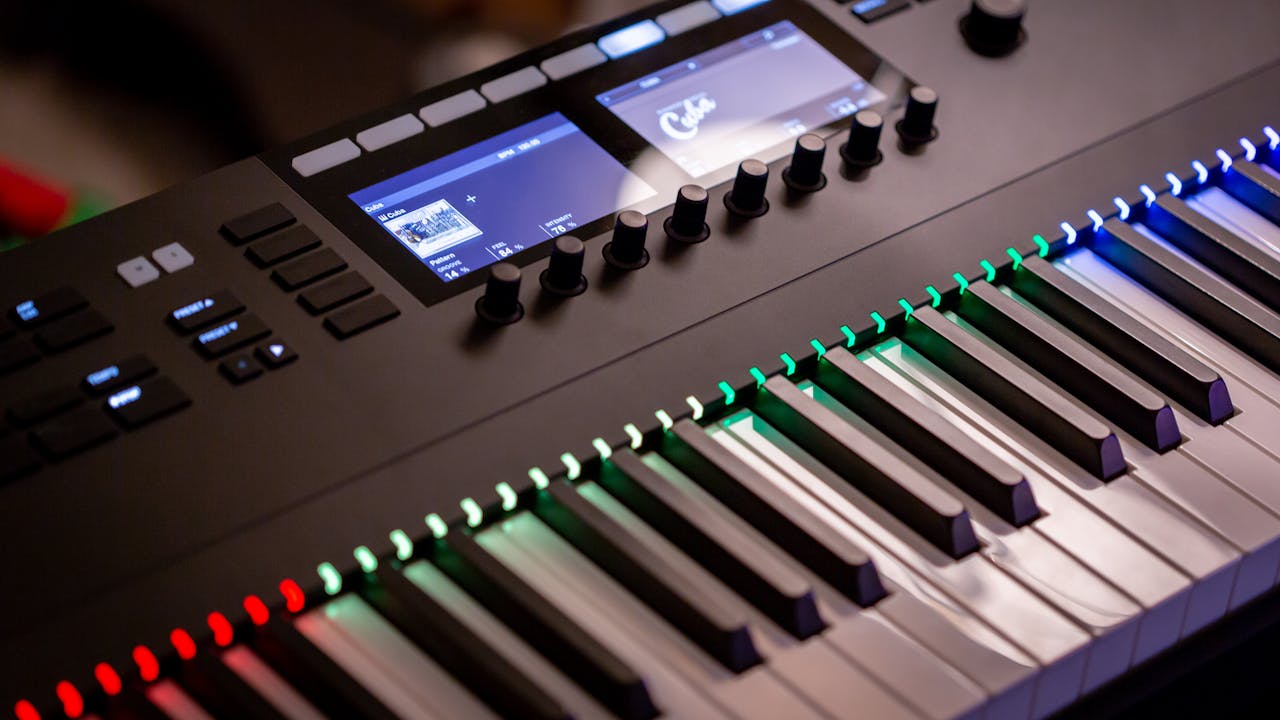 Close-up of an electronic keyboard with colorful illuminated keys in a studio setting.