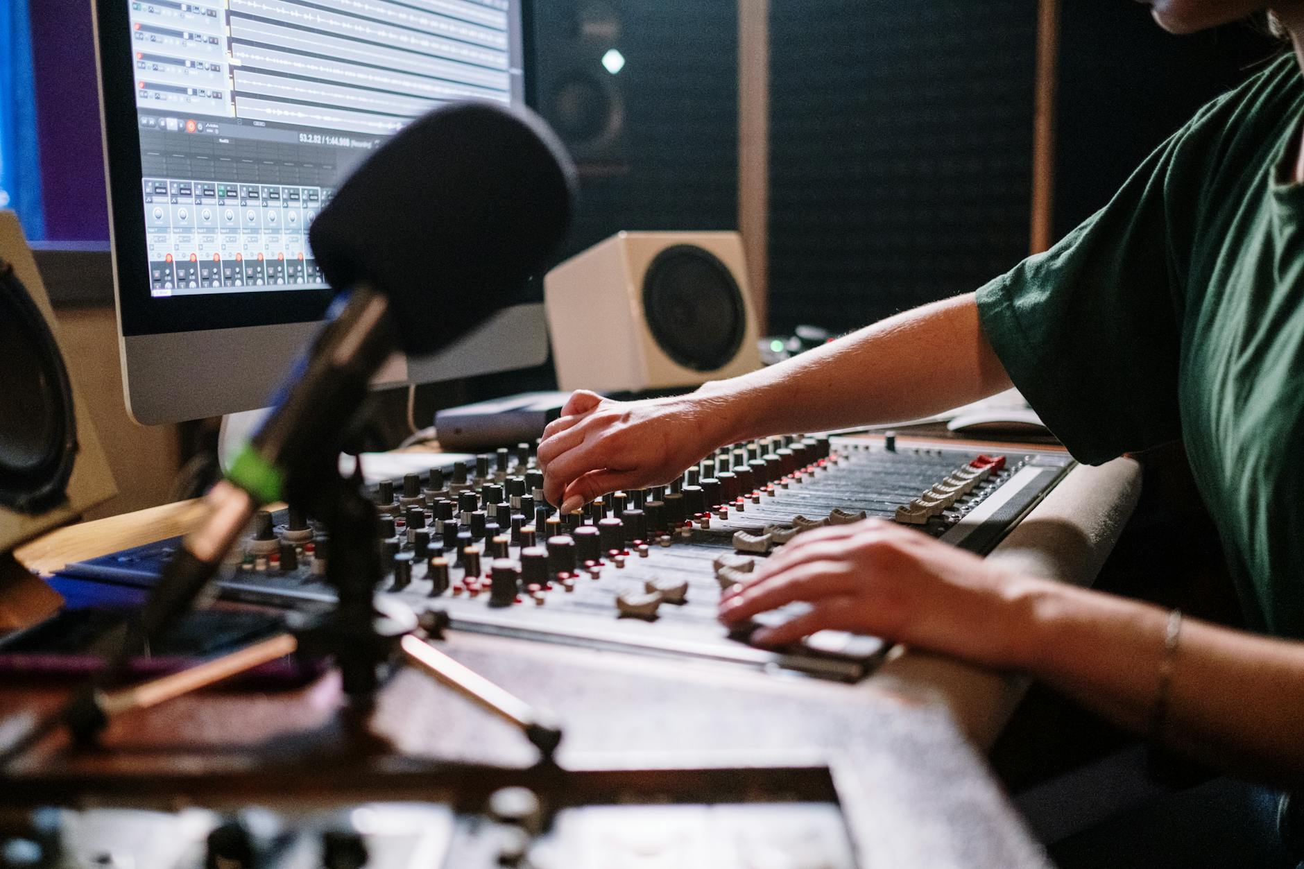 Professional audio engineer adjusting mixer in a modern sound studio.